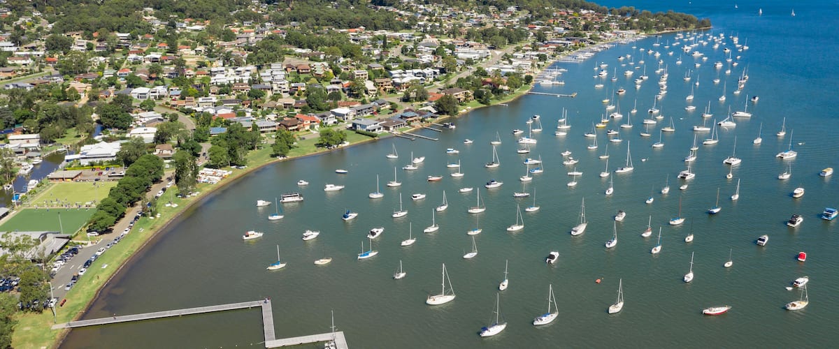 A coastal town with numerous sailboats docked along the waterfront.