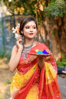 Portrait of pretty young indian girl wearing traditional saree and jewellery, holding powder colours in plate on the festival of colours called Holi, a popular hindu festival celebrated across india.
