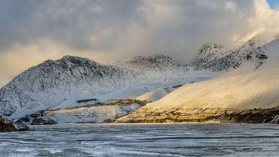 A snow-covered mountain range with a glacier in the foreground.