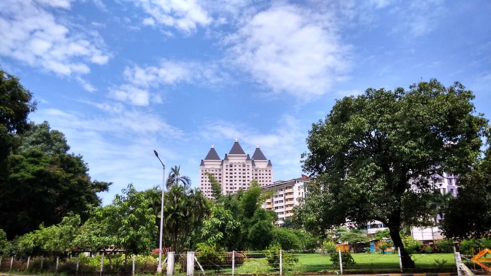 A large building with a distinctive architectural style, surrounded by lush green trees and a clear blue sky.