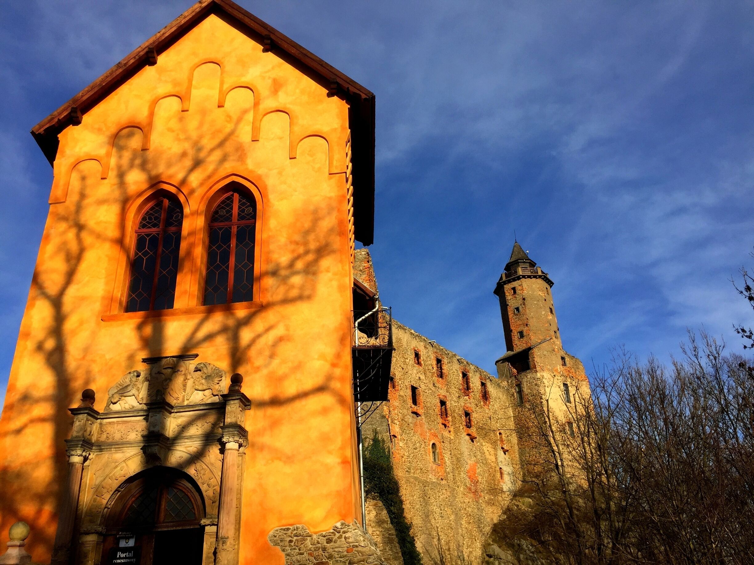 A church with a yellow facade and a stone tower.