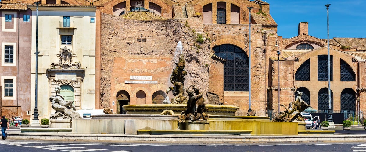 A historic building with a fountain and statues in front.