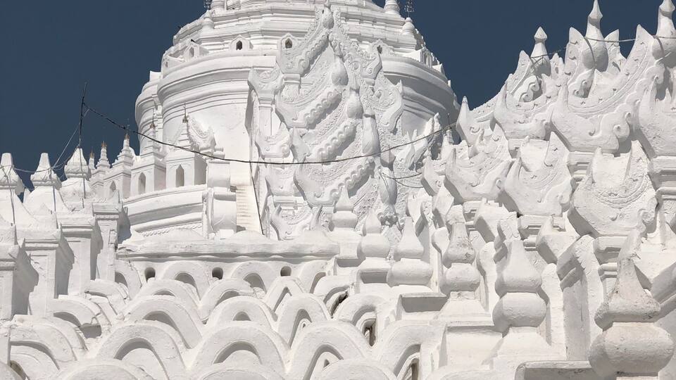 A white, intricately carved temple with tiered roofs and ornate decorations.