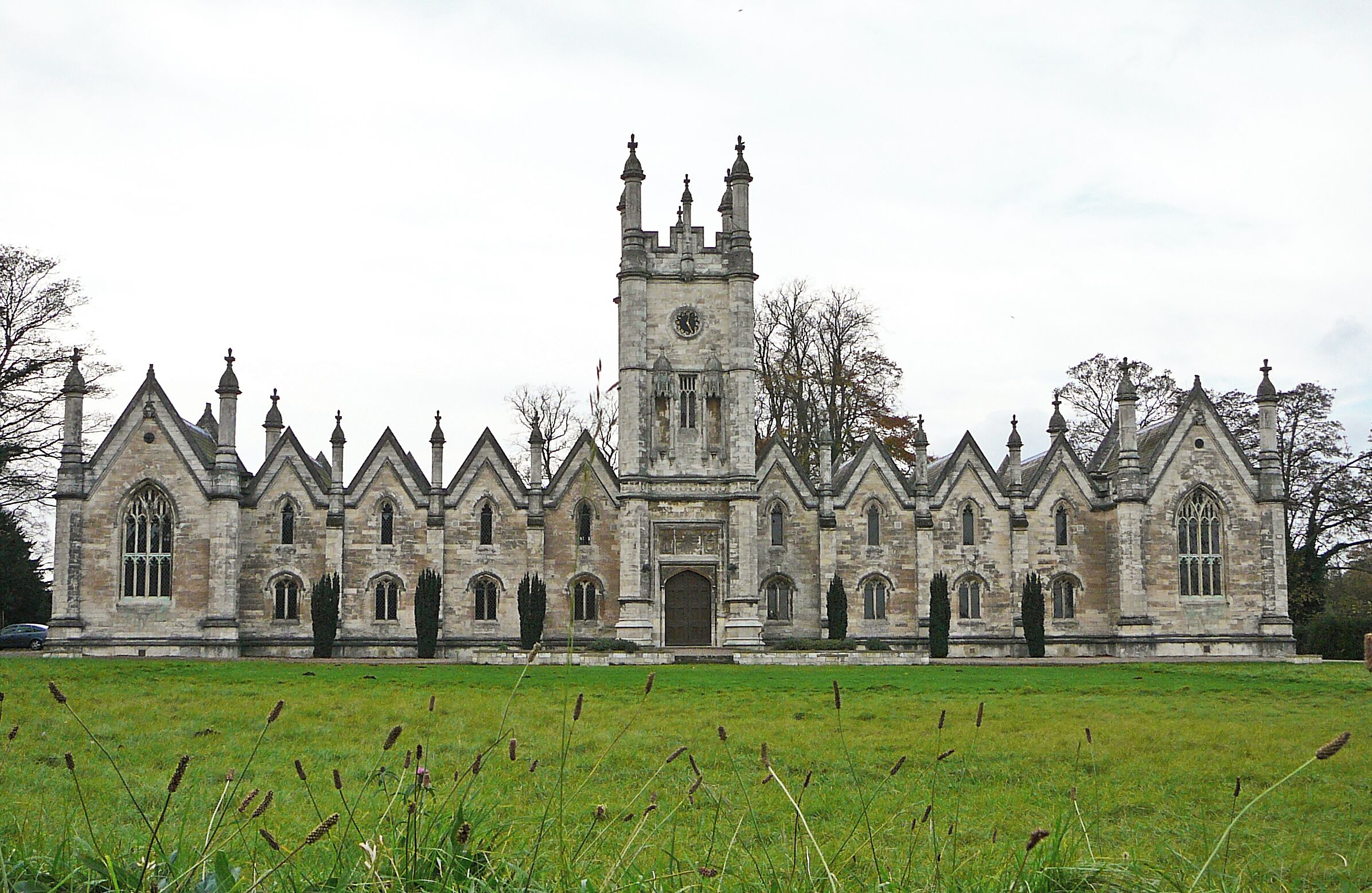 1843-5 by George Fowler Jones for Mary and Elizabeth Gascoigne as a memorial to their father and brothers. Now offices. Long ashlar front in Perp Gothic style, with elaborate central tower, many steeply pitched gables, and many outsize octagonal pinnacles. Projecting cross-wings with traceried windows, housing the chapel (l) and refectory (r), the domestic intermediate parts two-storied. Leach & Pevsner, The Buildings of England: Yorkshire West Riding (Leeds, Bradford and the North)