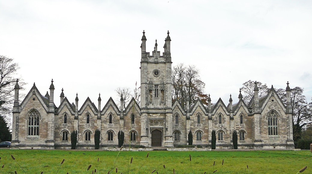 1843-5 by George Fowler Jones for Mary and Elizabeth Gascoigne as a memorial to their father and brothers. Now offices. Long ashlar front in Perp Gothic style, with elaborate central tower, many steeply pitched gables, and many outsize octagonal pinnacles. Projecting cross-wings with traceried windows, housing the chapel (l) and refectory (r), the domestic intermediate parts two-storied. Leach & Pevsner, The Buildings of England: Yorkshire West Riding (Leeds, Bradford and the North)
