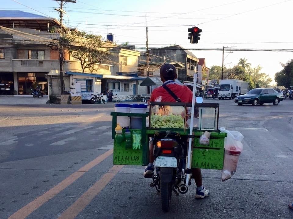Photo taken in my home City, Batac in Ilocos Norte, Philippines where a man in motorcycle stopped for the red light. This man is a Mango vendor as seen in the picture, he sells pickled mango for a living. #OnTheRoad Photo Contest