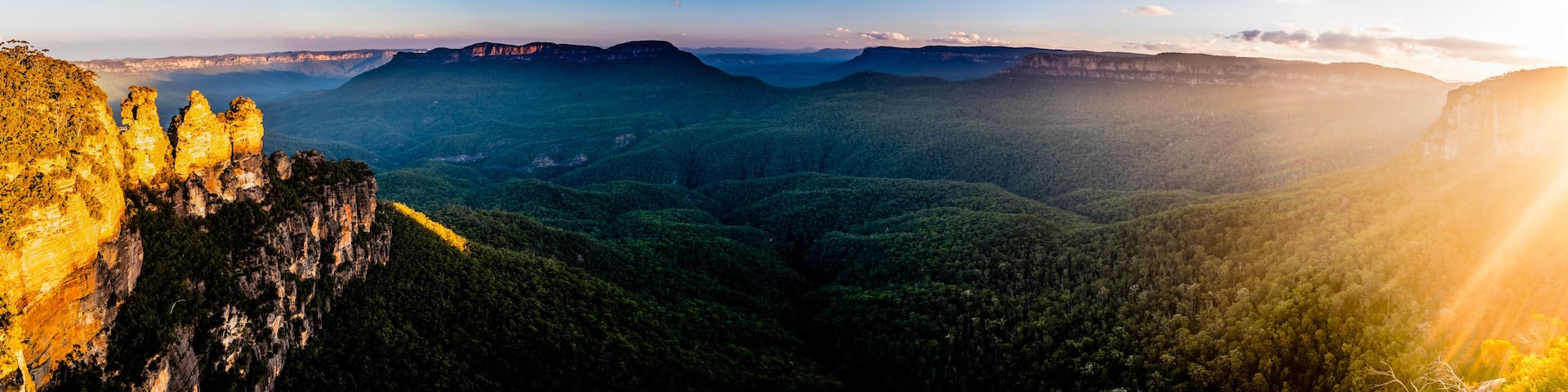 A mountainous landscape with a prominent cliff and dense forest.