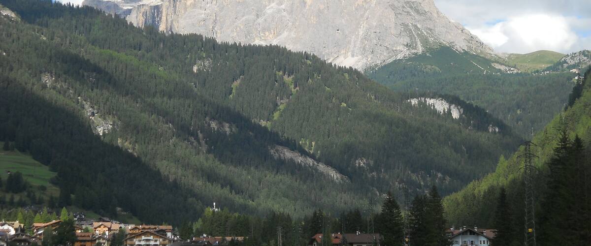 A mountain with a prominent peak, surrounded by dense forests and a small village at its base.