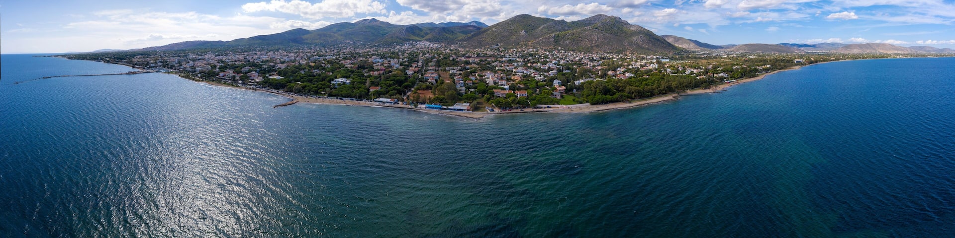 A coastal town with a mountain in the background and a clear blue sky.