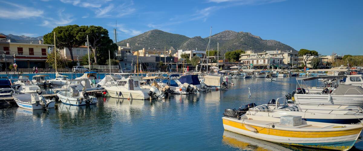 Nea Makri harbour, Attica Greece. Fishing boat moored in Aegean calm sea. Greek sun and blue sky.