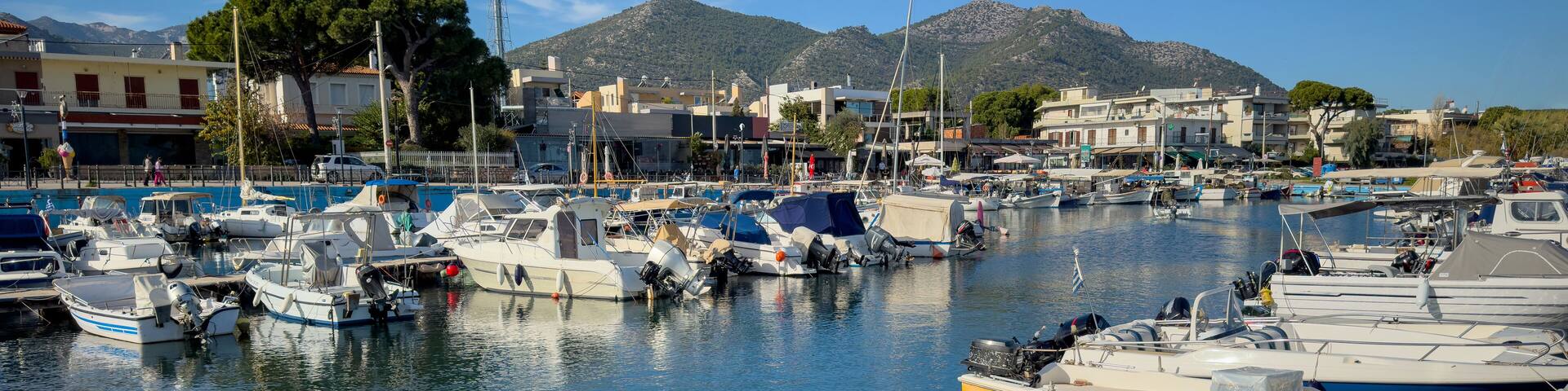 Nea Makri harbour, Attica Greece. Fishing boat moored in Aegean calm sea. Greek sun and blue sky.