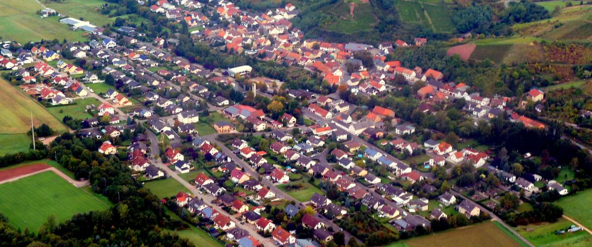 An aerial view of a rural village with houses, fields, and rolling hills.