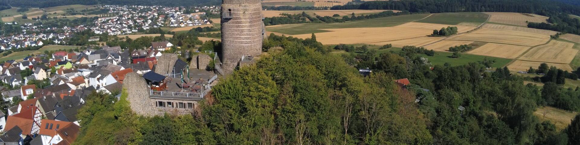 A historic tower surrounded by a village and rolling hills.