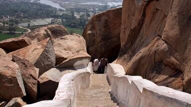 Una escalera de piedra que conduce a un mirador con vistas a un valle, un río y montañas lejanas.