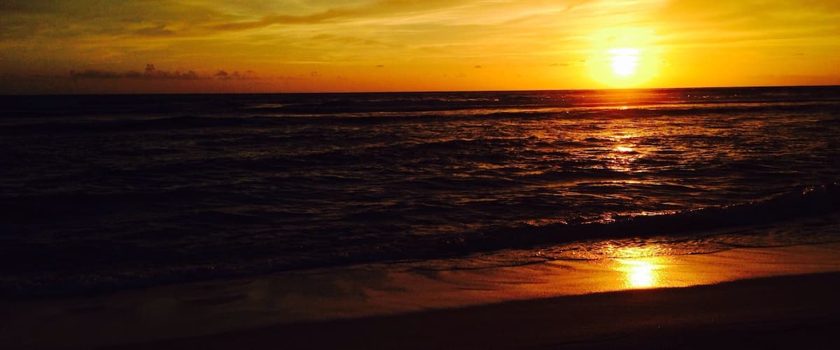 A sunset over the ocean with waves reflecting the sun's light.