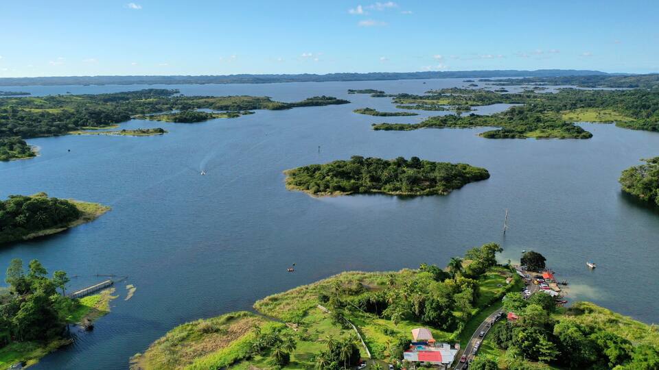 A large lake with several small islands, surrounded by lush greenery and a few buildings near the shore.