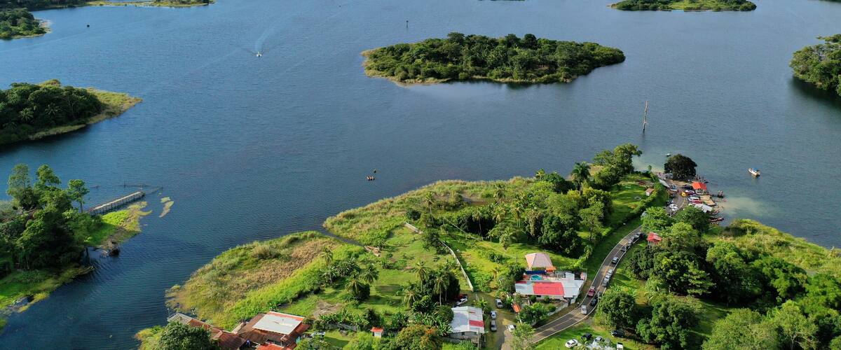 A large lake with several small islands, surrounded by lush greenery and a few buildings near the shore.