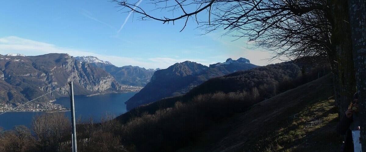 A mountainous landscape with a town in the valley, a lake, and several cars parked on a road.