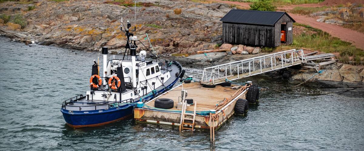 A blue and white boat docked at a wooden pier with a small shed in the background.