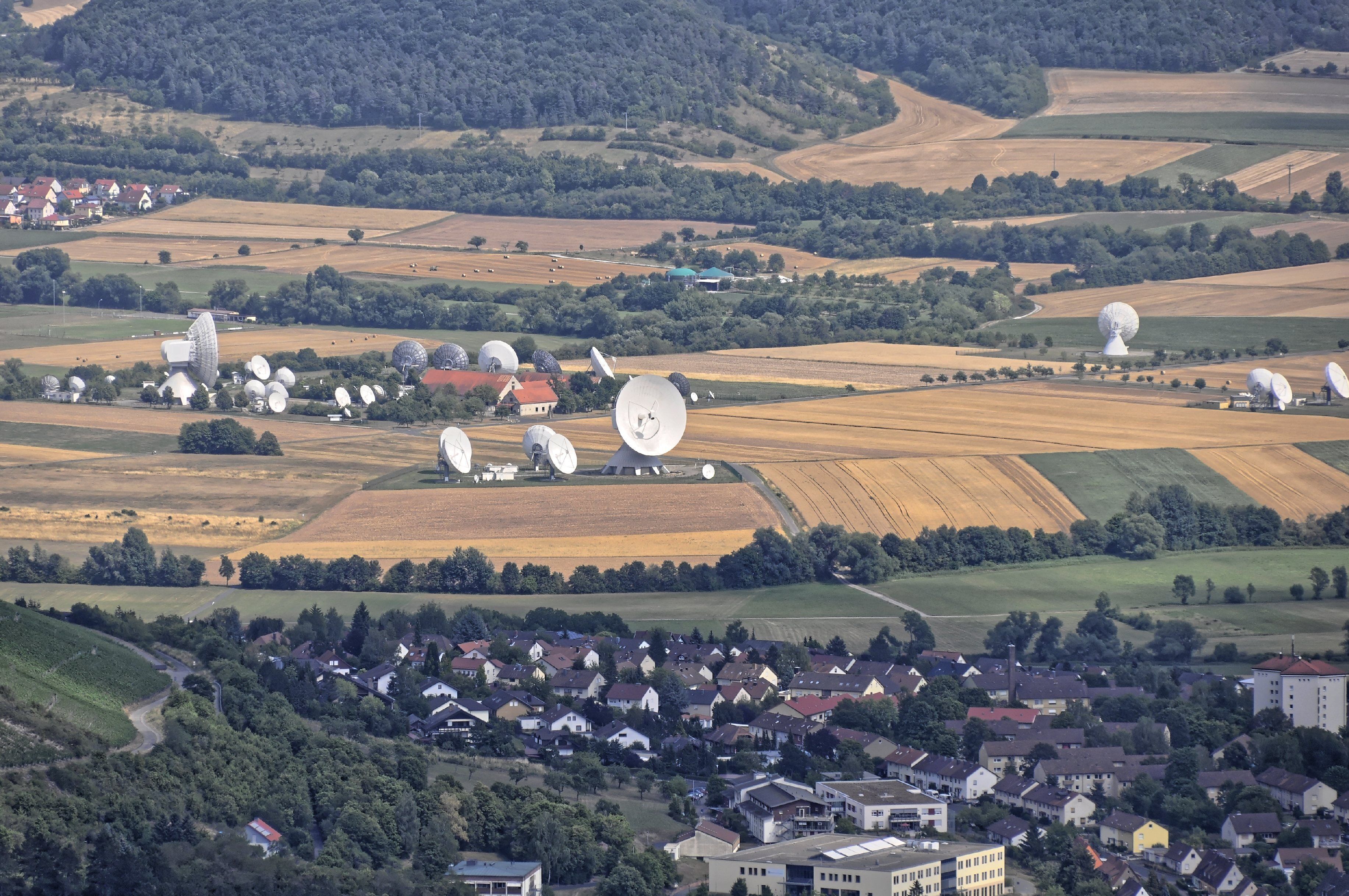 A rural landscape with fields, a village, and multiple large satellite dishes.