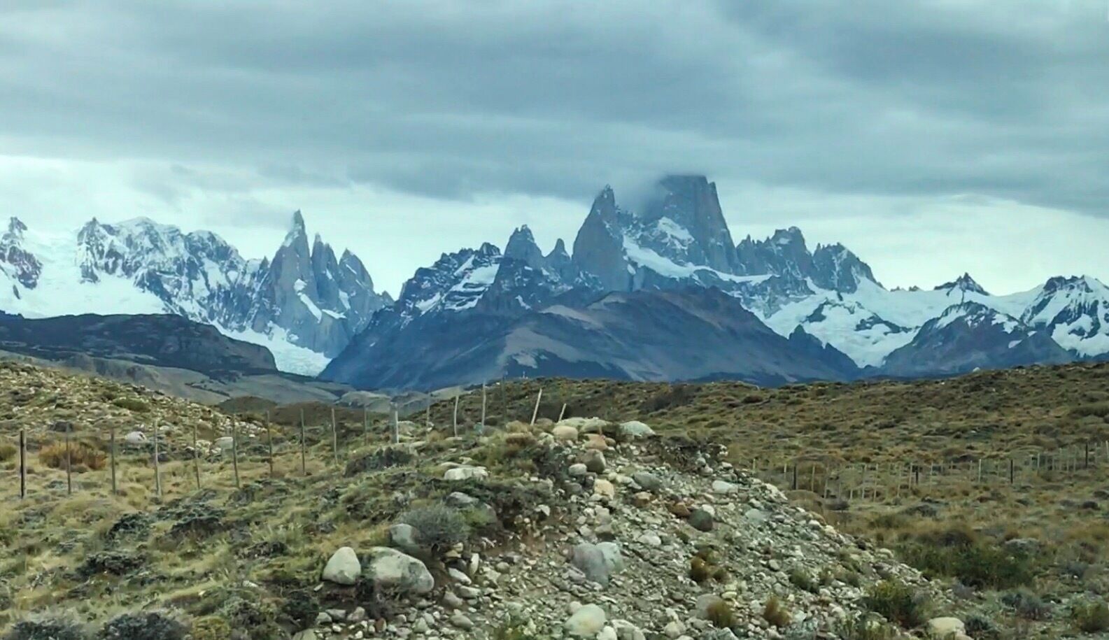A mountainous landscape with snow-capped peaks and a rocky foreground.
