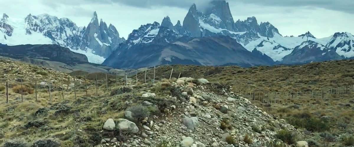 A mountainous landscape with snow-capped peaks and a rocky foreground.