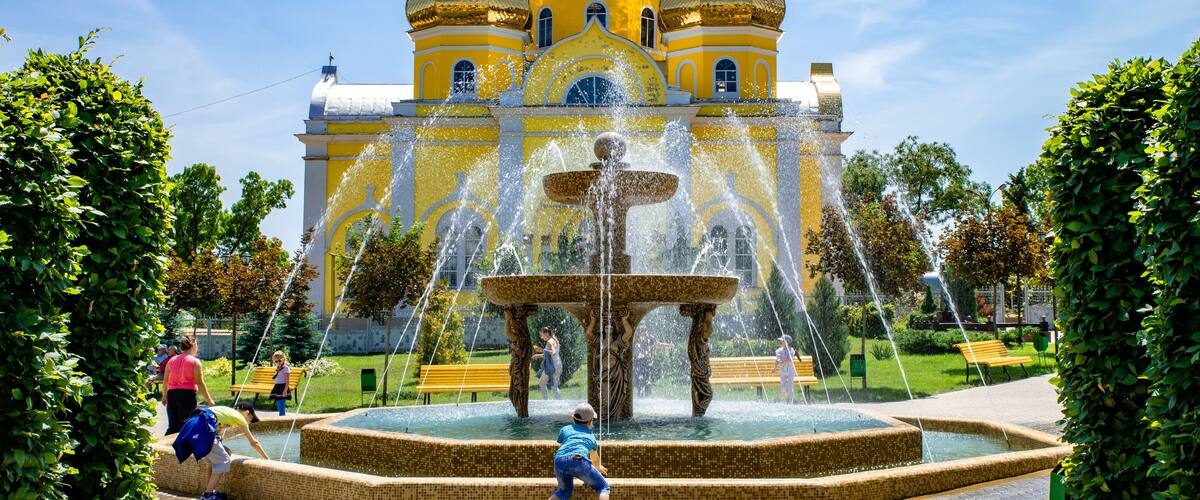 A historic yellow-domed building with a central fountain.