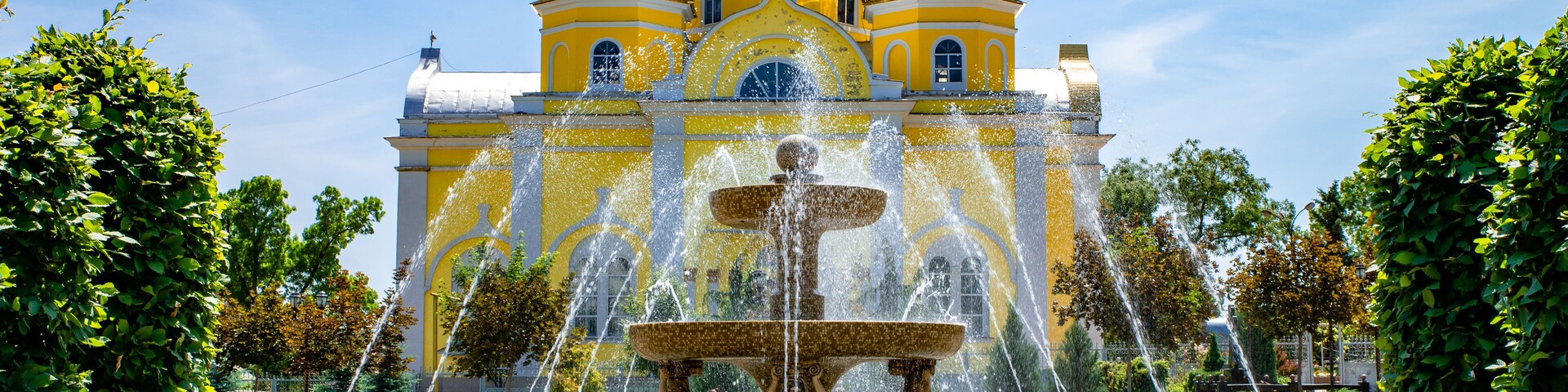 A historic yellow-domed building with a central fountain.
