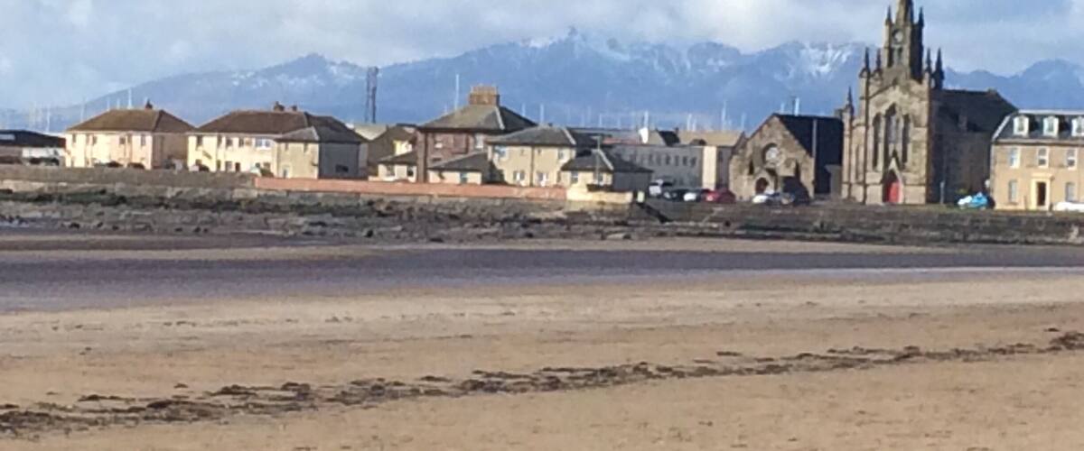 A coastal town with a church and mountains in the background.