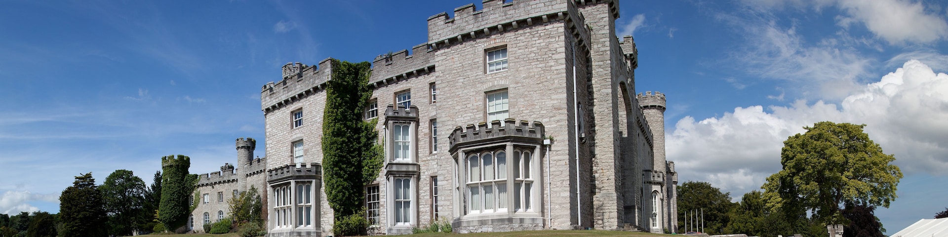 A large stone castle with a grassy lawn in front.
