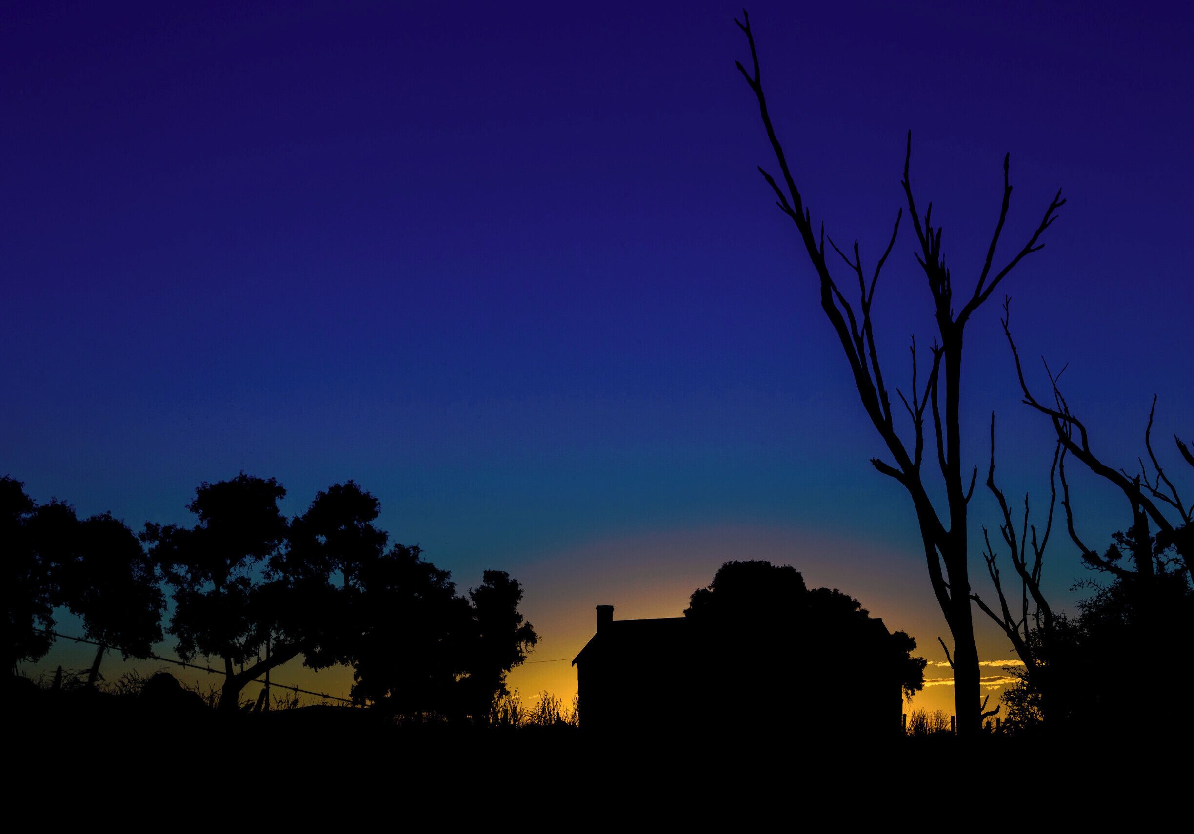 A silhouette of a house against a twilight sky with a gradient from blue to orange.