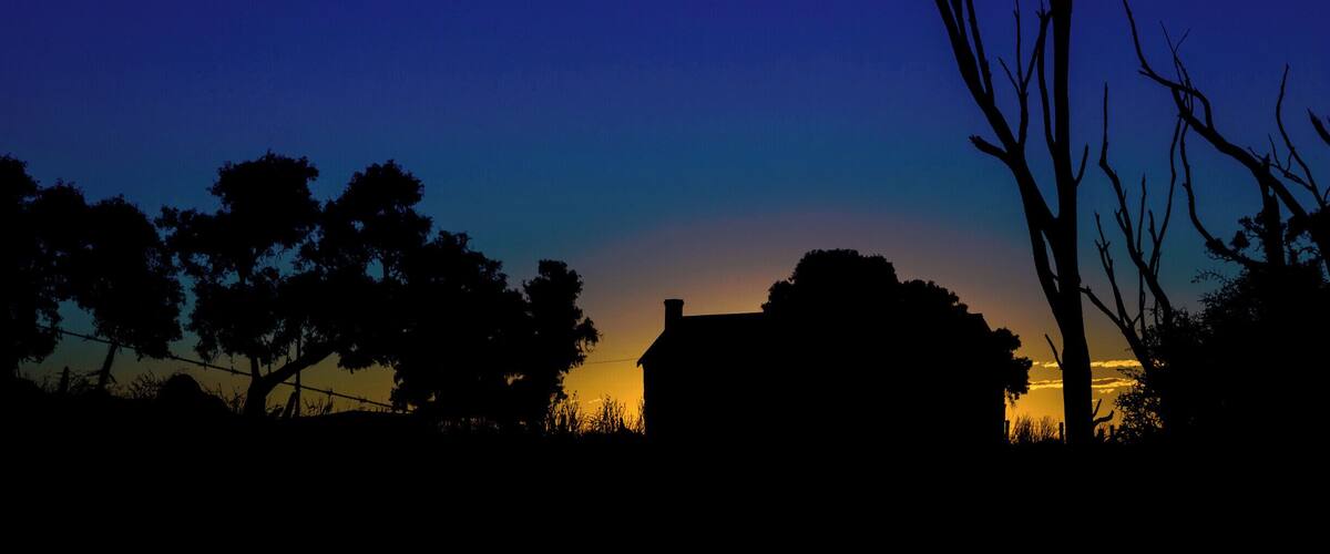 A silhouette of a house against a twilight sky with a gradient from blue to orange.