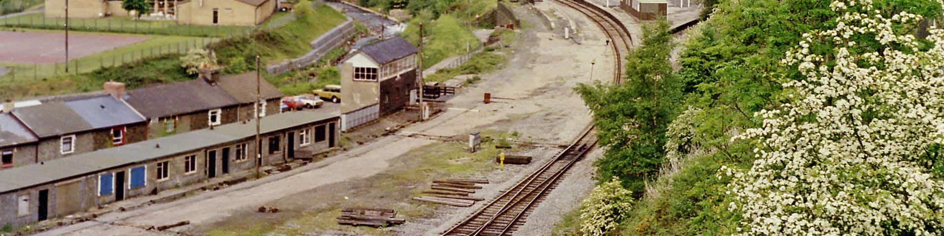 Junction at Aberbeeg of railways and valleys, 1990. View NW from the A463 road up the Ebbw Valley, towards Ebbw Vale (to the left, Ebbw Fawr), with the railway still open - just about) and to the right up the Ebbw Fach valley to Abertillery, Nantyglo and Brynmawr. In this 1990 view it appears that there are still station platforms for both routes, but the station had been closed for passengers on 30/4/62 and for goods from 28/11/66. The line up the Ebbw Fawr remained open to serve Ebbw Vale Steelworks and a passenger service to Ebbw Vale - but not stopping here - was restored on 6/2/08. The line to the right to Nantyglo and Brynmawr was closed from 30/4/62, although goods to Abertillery continued until 7/4/69, but it still seems to exist here in 1990.