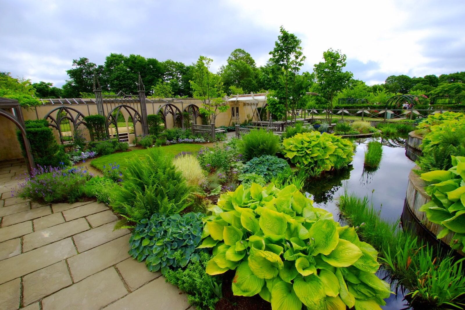 A garden with a pond, lush greenery, and a gazebo.