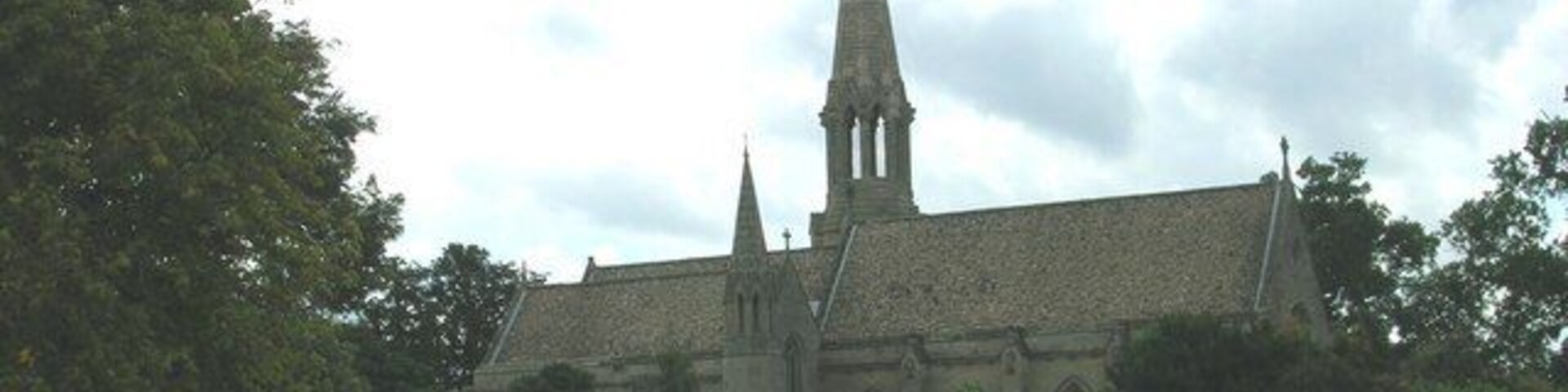 Una iglesia con una aguja alta y fachada de piedra.