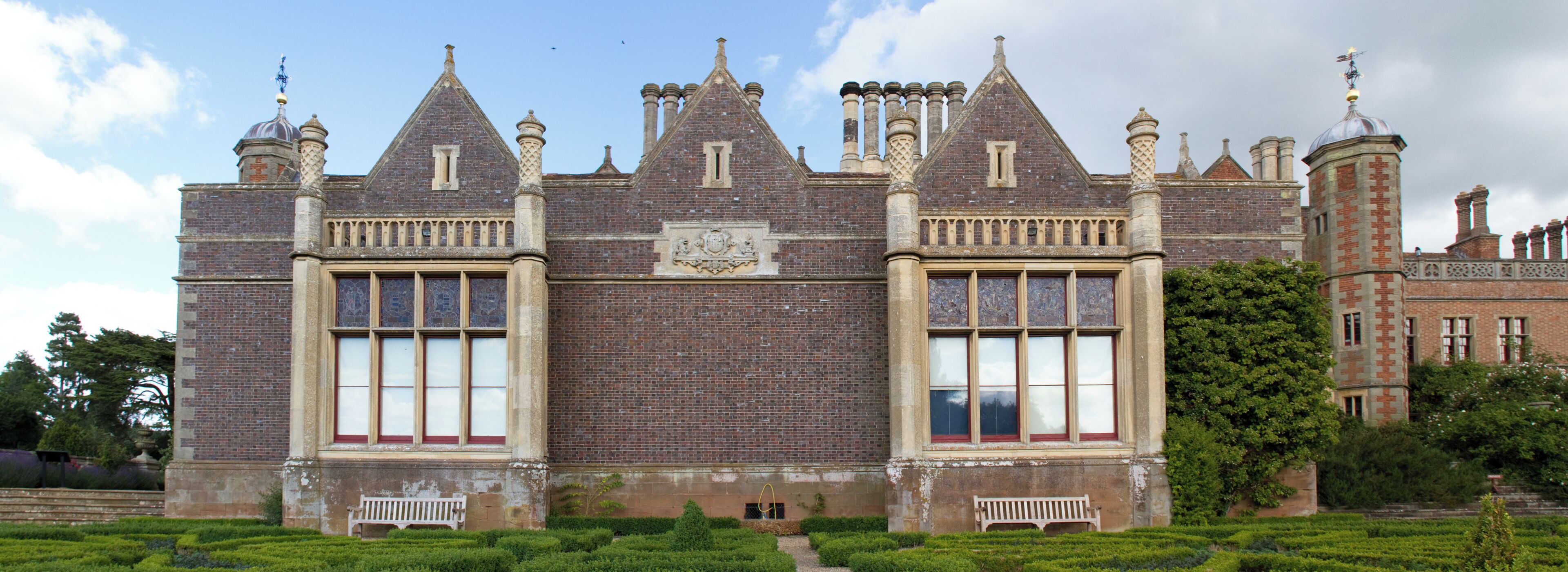 A large, historic building with a symmetrical facade, large windows, and a central emblem.
