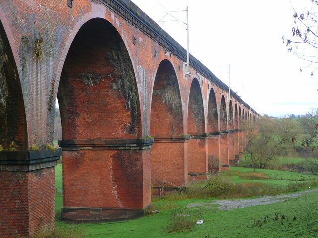 A long brick viaduct with multiple arches spanning a green landscape.