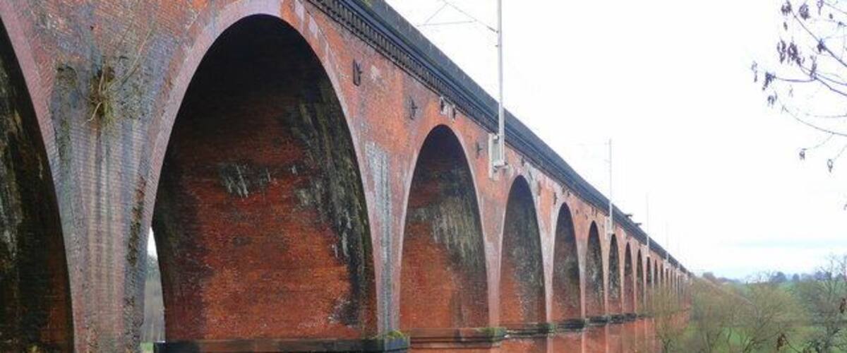 A long brick viaduct with multiple arches spanning a green landscape.