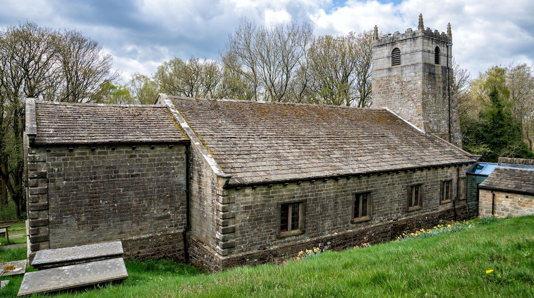 A historic stone building with a tower, surrounded by trees and grass.