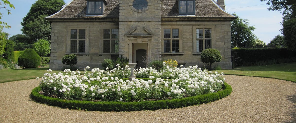 A large stone house with a symmetrical facade, a central entrance, and a circular window above the door.