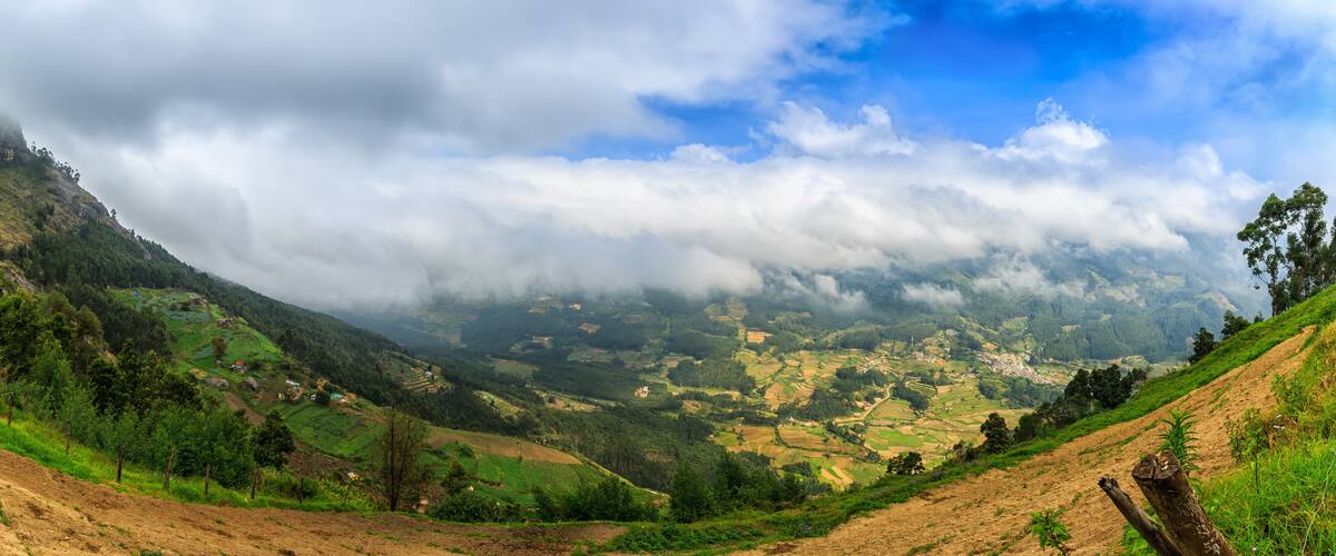 A mountainous landscape with terraced fields, a village, and a forested area.