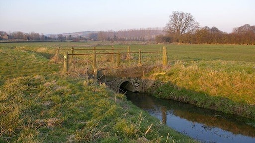 Bridge over drainage ditch, Wigmore Moor This is one of a number of drainage ditches on Wigmore Moor, a small area of levels south of the River Teme. In the background near the left hand edge of the photo are the remains of Wigmore Abbey.