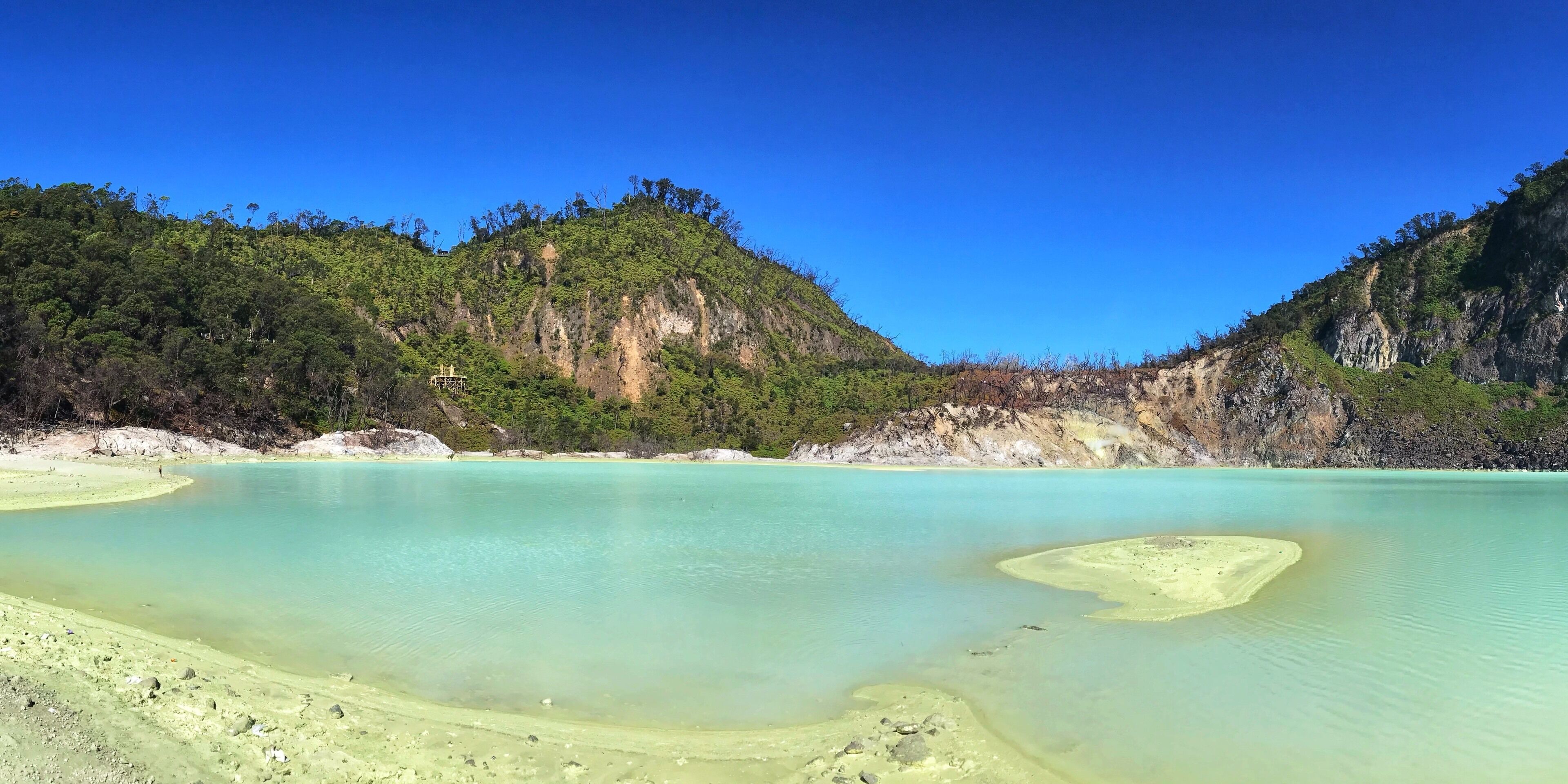 A turquoise lagoon surrounded by forested hills.