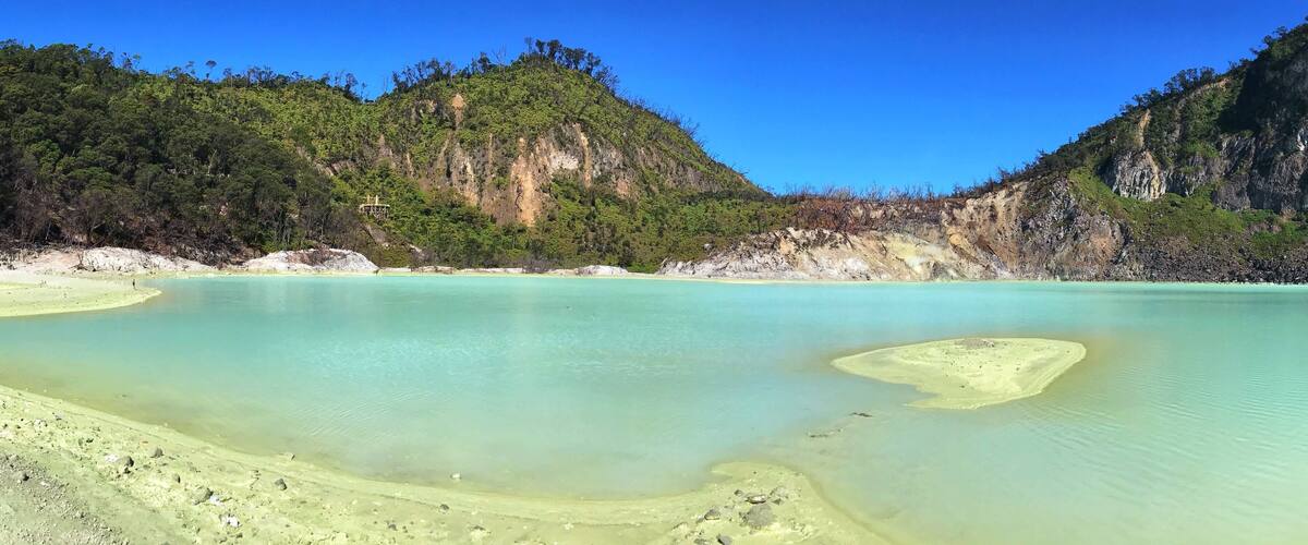A turquoise lagoon surrounded by forested hills.