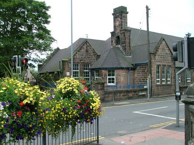 A stone building with a chimney, a traffic light, and a flower bed with yellow and purple flowers.