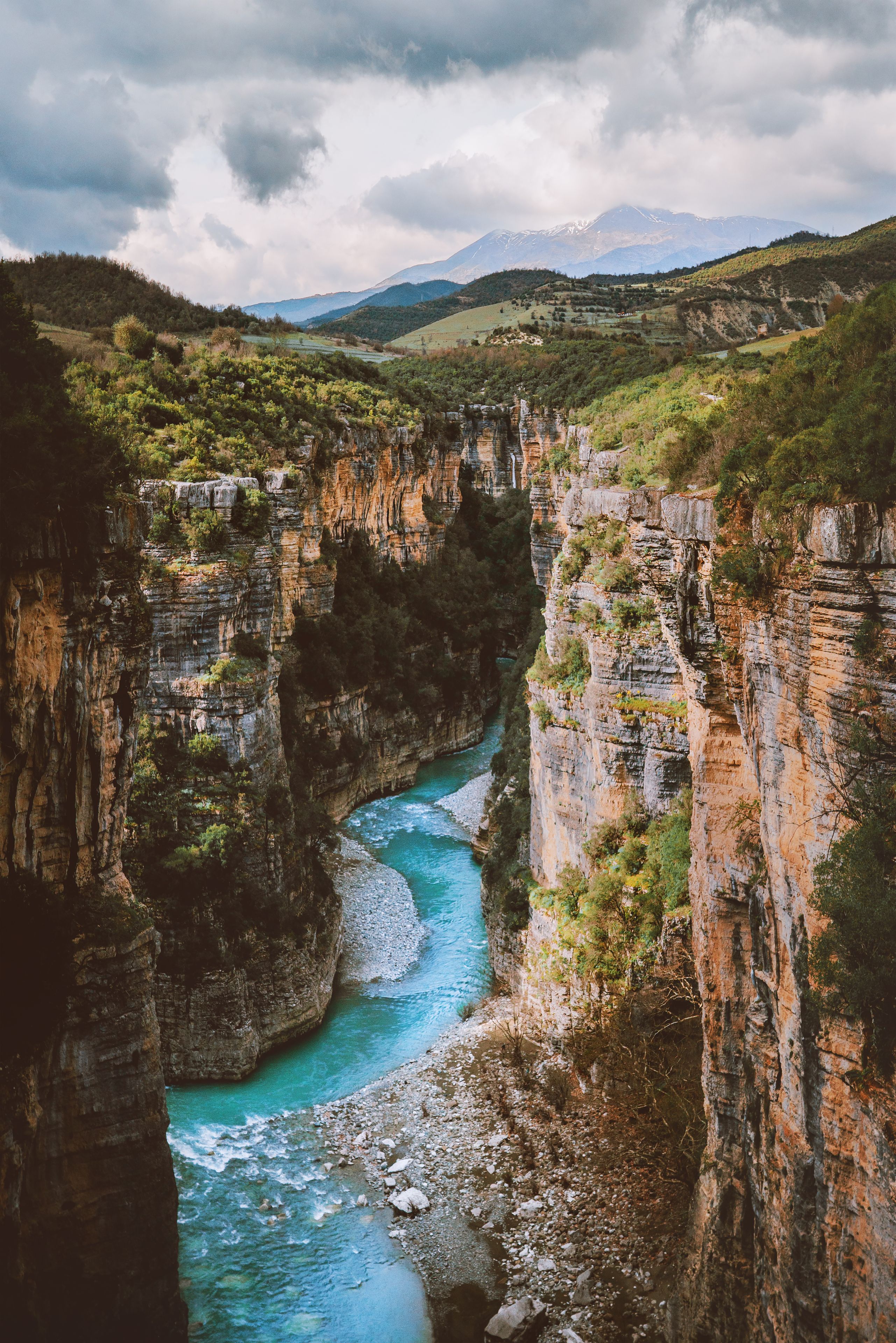 Une rivière qui traverse un canyon aux parois abruptes, avec des montagnes en arrière-plan.