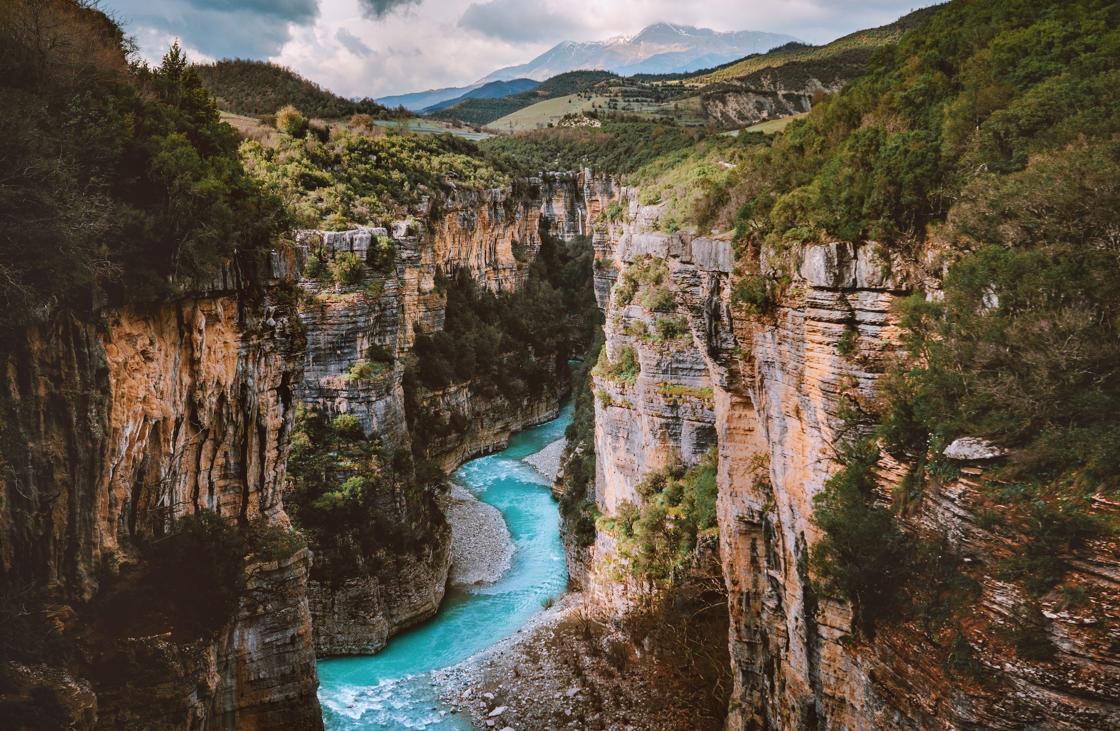 Un canyon traversé par une rivière, avec des falaises abruptes et un paysage montagneux en arrière-plan.