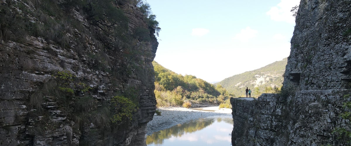 Un canyon étroit aux parois rocheuses abruptes, où une rivière paisible reflète le ciel.