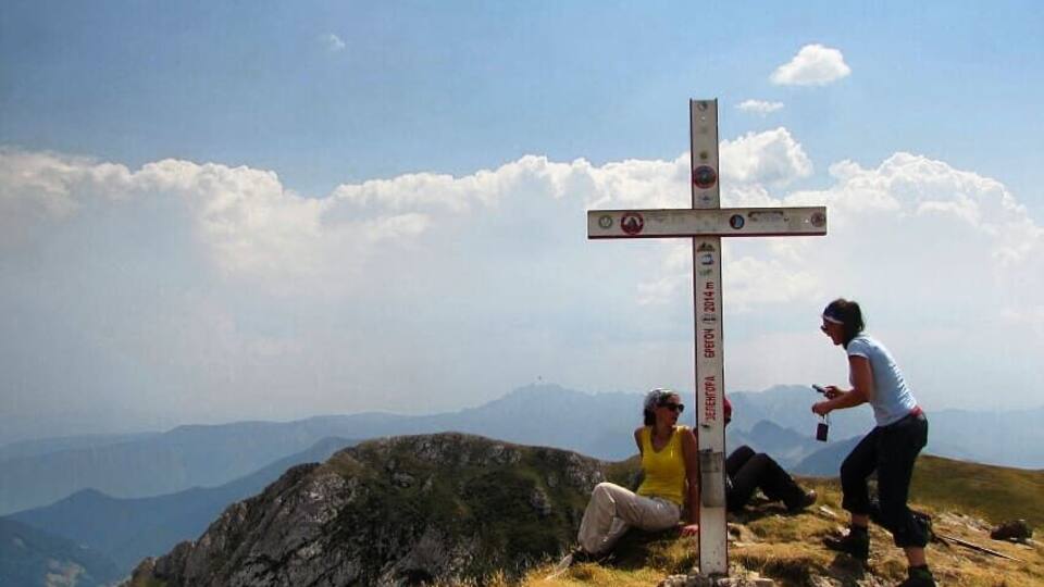 A cross on a mountain peak with a clear sky and distant mountains.