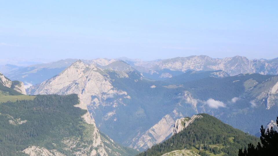 A mountainous landscape with rugged peaks and dense forests.